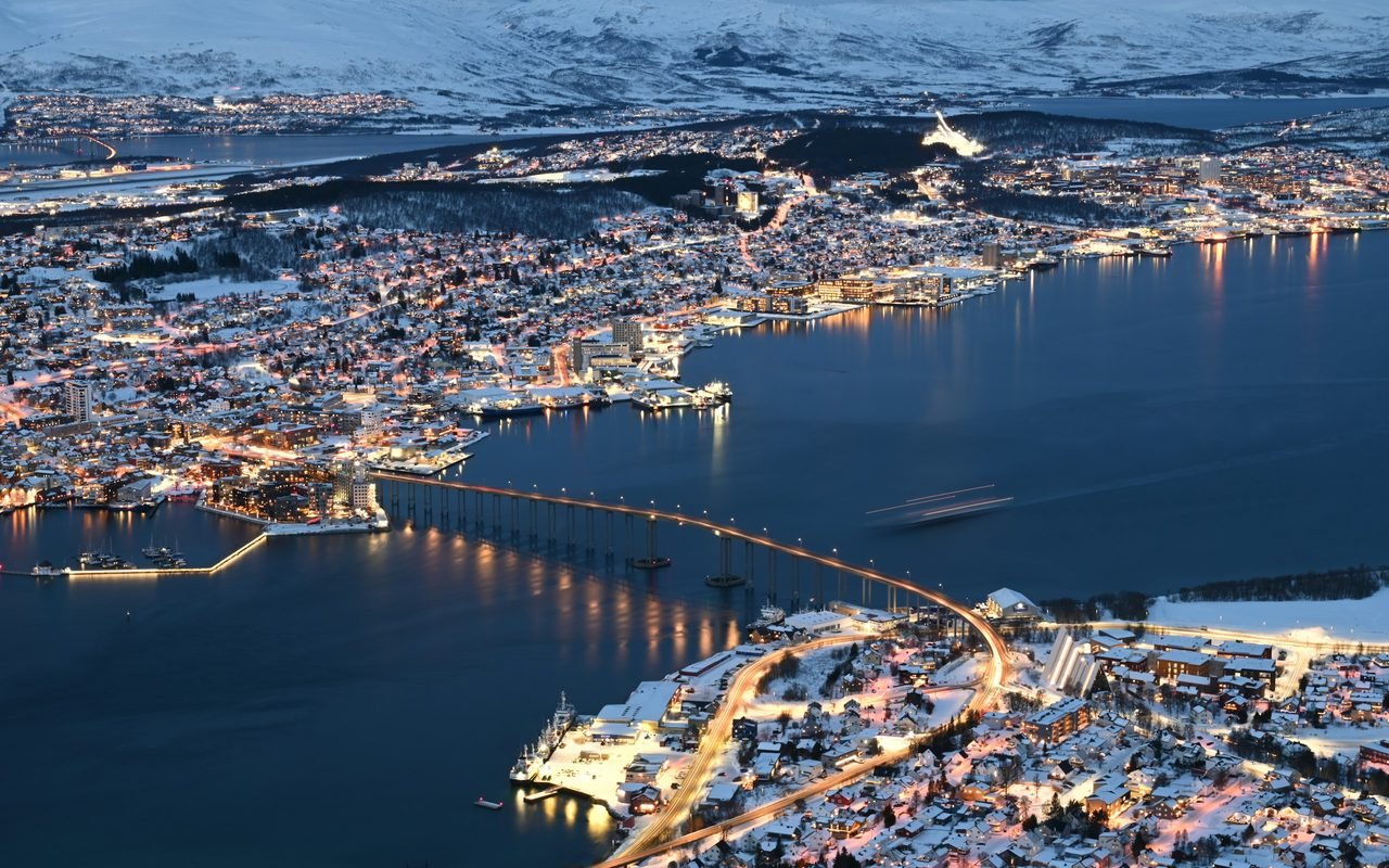 Tromsø and the Tromsø Bridge lit up at dusk in winter